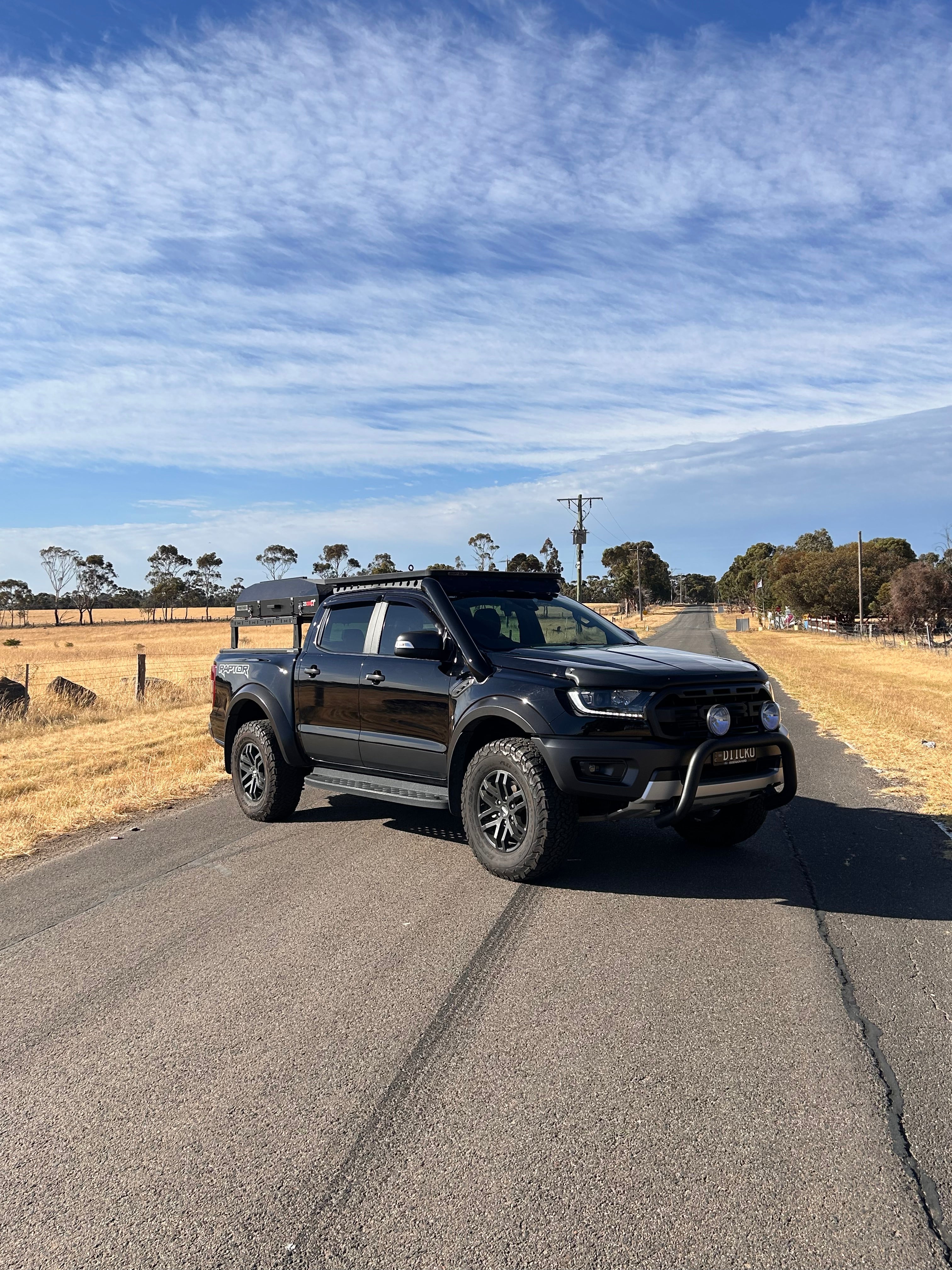 Black Ford Ranger Raptor PX3 on the road showing Canna Fabrication stainless snorkel — rear three-quarter view