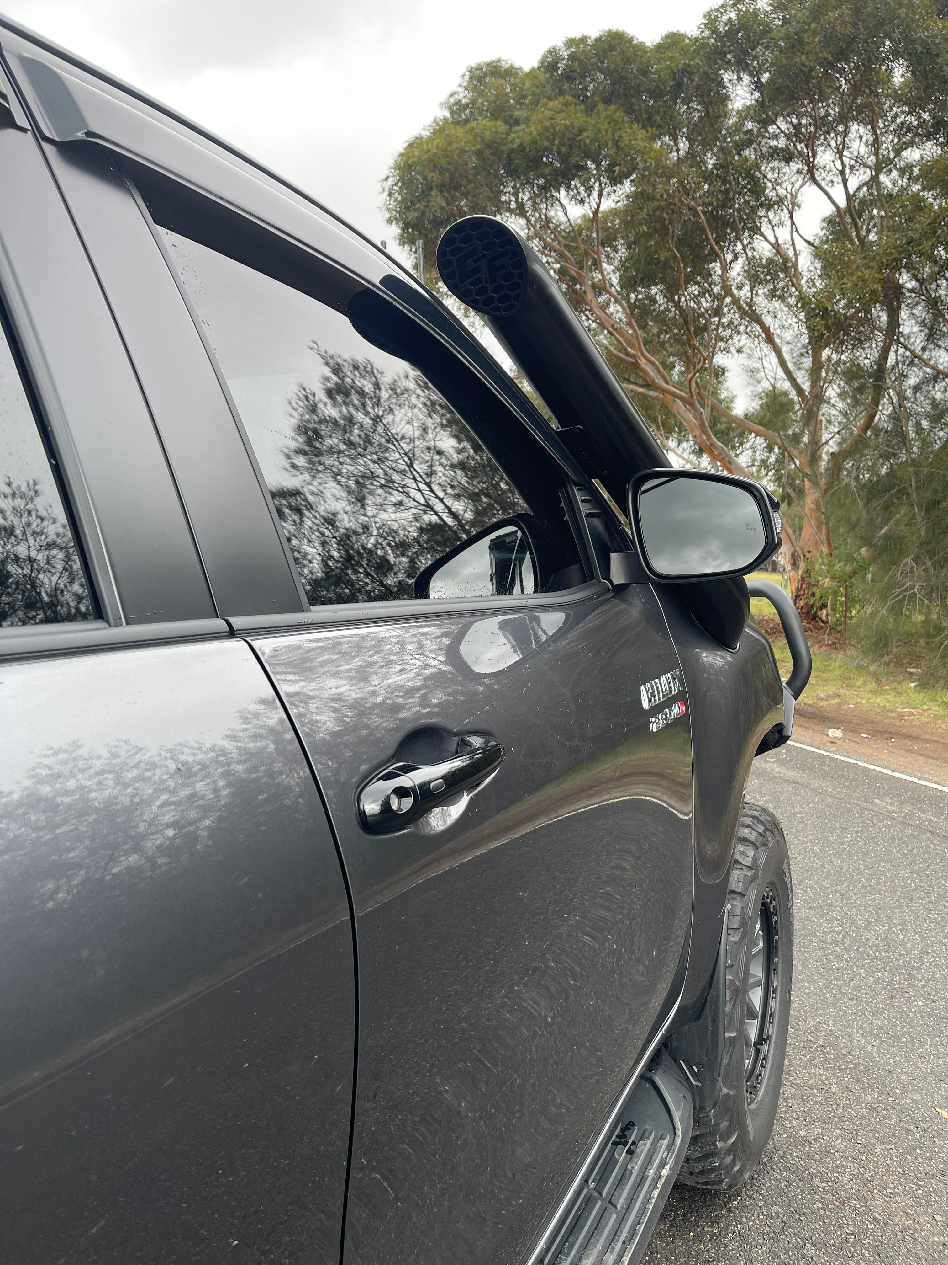 Canna Fabrication stainless snorkel on a grey Toyota Hilux N80 — A-pillar detail