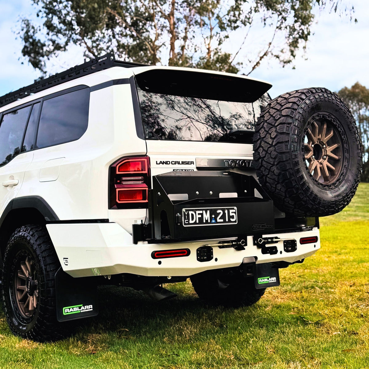 This is an image of the 250 Series Prado Toyota Landcruiser Rear Bar and Wheel Carrier setup by Raslarr Engineering Made in Australia White Black HERO photo blue red silver angle wheel carrier