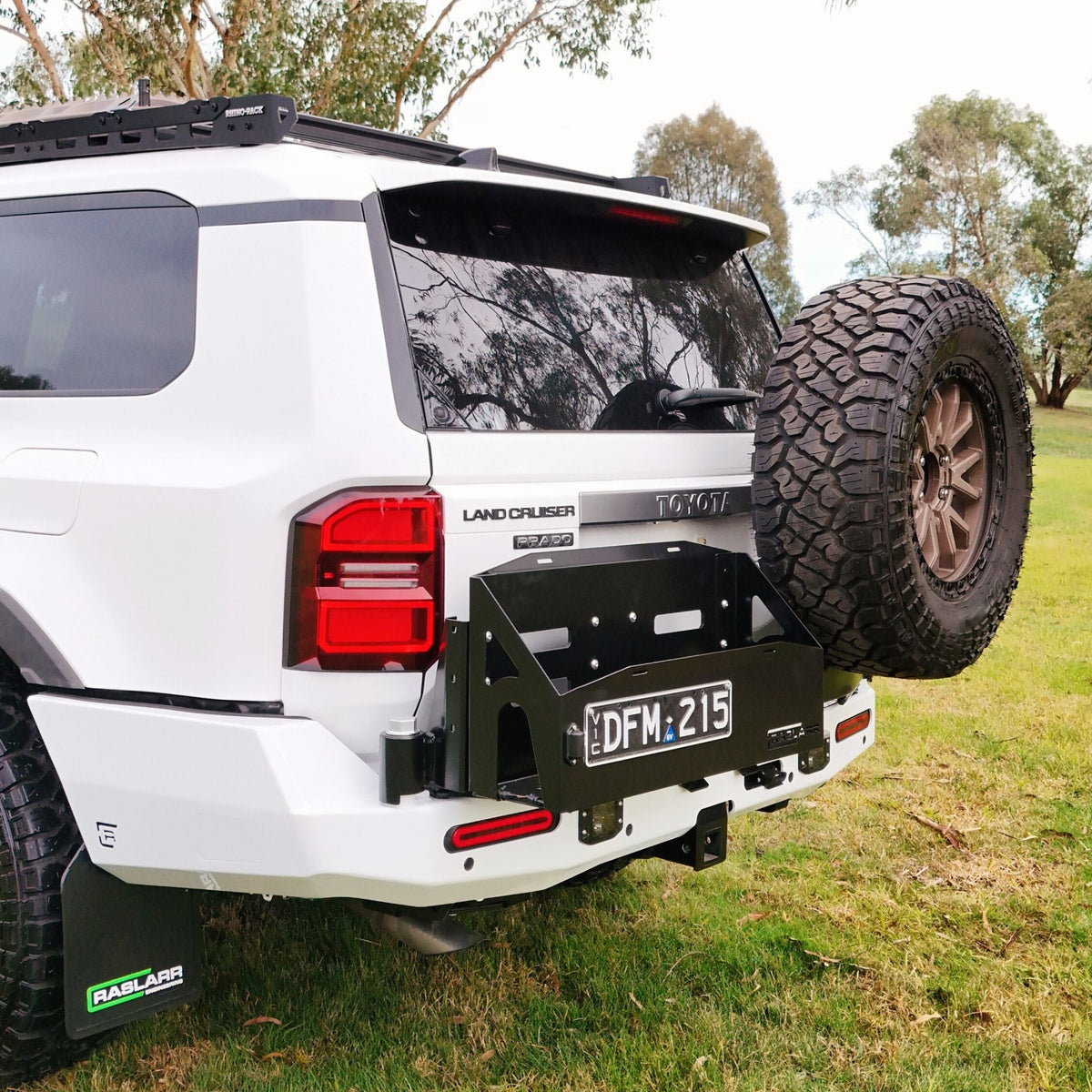 This is an image of the 250 Series Prado Toyota Landcruiser Rear Bar and Wheel Carrier setup by Raslarr Engineering Made in Australia White Black HERO photo blue red silver angle wheel carrier
